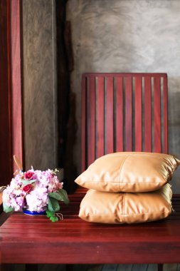Kahve dükkanı alanı, sarı yastık ve ahşap masanın üzerinde güzel pembe çiçeklerle rahatla. Çatı katı tarzı tasarım ve dekorasyon. Sevgililer Günü Kavramı.