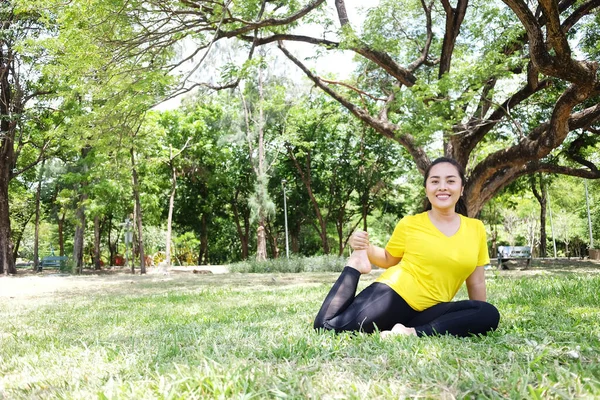 在自然光花园里 穿着黄色运动鞋的亚洲年轻女子坐着微笑 做瑜伽冥想 让你集中精神 让你的心灵在草地上平静 — 图库照片