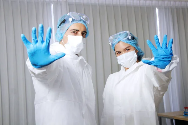 Powerful of Medical team in Personal Protective Equipment or PPE clothing and Healing for patient and showing stop hand sign for Covid-19 virus pathogens and inhibit the spread of germs.