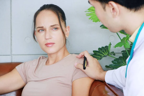 Genç Asyalı erkek psikiyatrist, psikiyatri uzmanı. Kafkas kadın hastasının omzuna dokunuyor ve duygusal semptomlar için klinik tedavi uyguluyor..