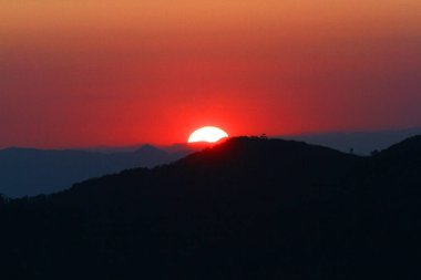 Gökyüzünde ve bulutta gün batımı, güzel rengarenk alacakaranlık zamanı dağ siluetiyle.