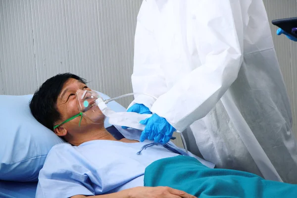 Kişisel Koruyucu Ekip ya da PPE giysileri ve Asyalı yaşlı hasta için solunum cihazı kullanmak Covid 19 virüsü ile enfekte olmuş solunum sistemi ve tedavi için tabletle yapılan araştırmalar.