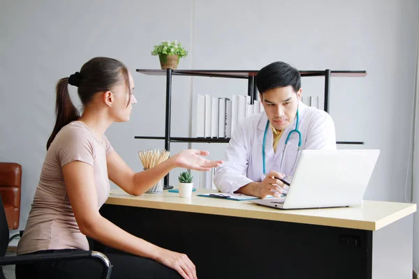 Young Asian male psychiatrist is specialist in psychiatry Caucasain female Patient serious together for therapy and talking for encourage with laptop in Clinical treatment for emotional symptoms.