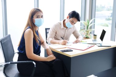 Kovid19 virüsünü önlemek ve iş yerinde beyin fırtınası yapmak için maske takan Asyalı iş adamları. İş konseptinde sağlık ve yeni normal yaşam tarzı.