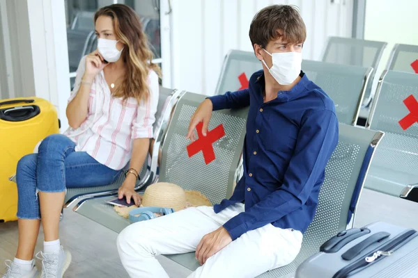 Ciddi Genç Kafkasyalı gezgin çift maske takıyor ve havaalanında uçak rötar yaptığı için yolcu koltuğunda birlikte oturuyorlar. Tatil için balayı gezisi.