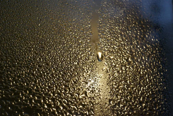 water drops on wet window glass with city lights