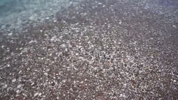 Pure vague de mer transparente sur une plage de galets.