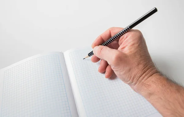 Mano Masculina Con Lápiz Escribe Una Hoja Cuaderno Cuadros Enfoque — Foto de Stock