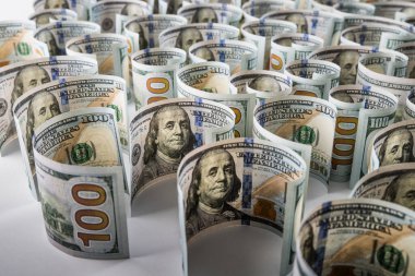 100 dolarlık banknotların yakın plan çekimleri beyaz arka planda yuvarlandı.