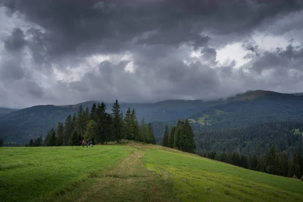 Çimleri biçilmiş dağ manzarası, saman yığınları ve kara yağmur bulutları