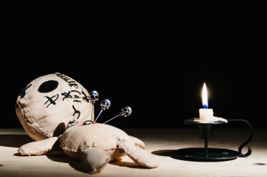 Sihirli ayinin için siyah bir arkaplanda mumla kafatasları olan iğneler vudu bebeğine saplandı.