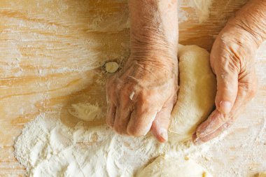 Evde yemek yapmak, yaşlı bir kadının elleri hamur yoğurmak.