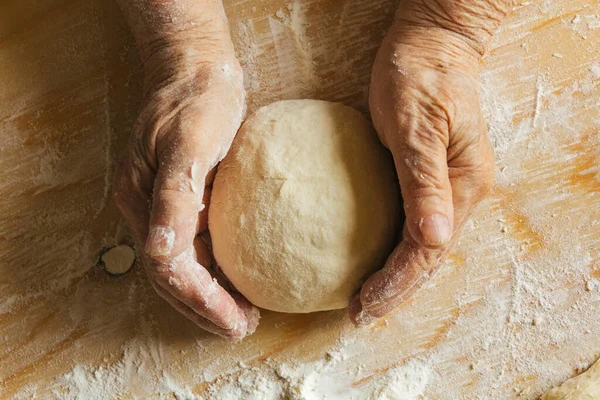 Evde yemek yapmak, yaşlı bir kadının elleri hamur yoğurmak.