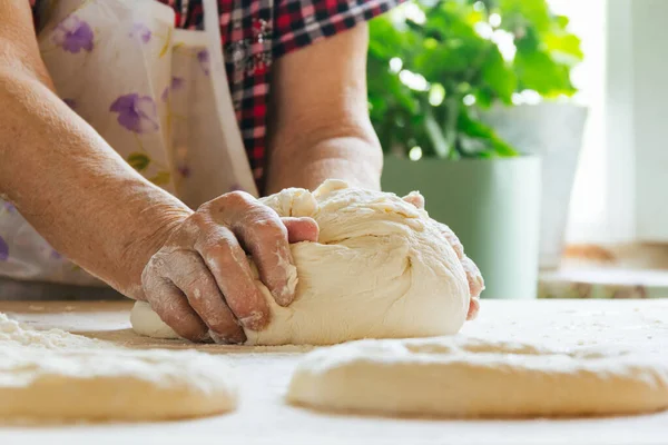 Evde yemek yapmak, yaşlı bir kadının elleri hamur yoğurmak.