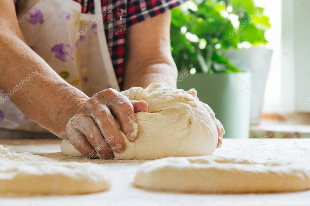 Cooking at home, old woman's hands kneading dough