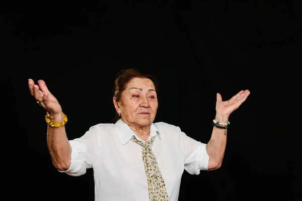 Portrait of an elderly senior Asian woman, raising her hands in a question gesture, like saying; 