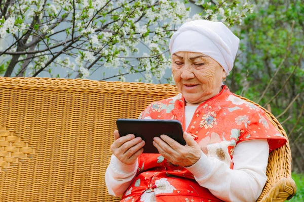 Portrait of a smiling Asian elderly woman watching into a tablet in her hands