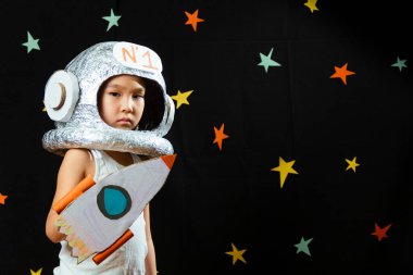 Küçük şirin bir Aisan kızının portresi, evde boş yer, hayal kurma ve astronotçuluk oynama. Komik aile anları