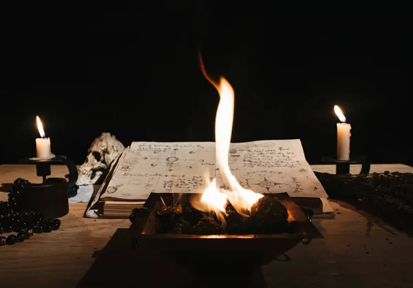 Occult white magic ritual of fire using grimoire, old book, candles