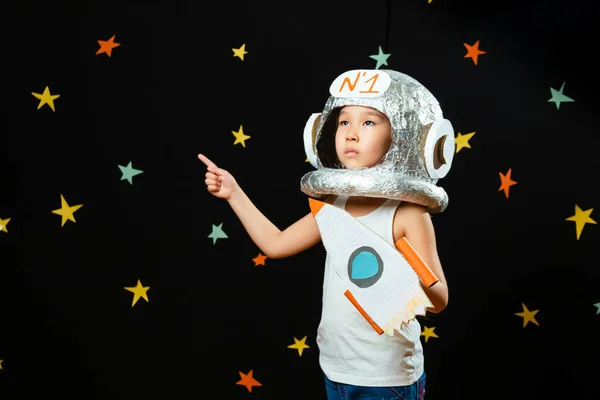 Küçük şirin bir Aisan kızının portresi, evde boş yer, hayal kurma ve astronotçuluk oynama. Komik aile anları