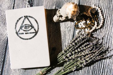 Masanın üzerinde beyaz büyü kitabı ve lavanta ile birlikte yatıyordu. Falcılık, ritüel, sunak, maneviyat, gizli bilgi