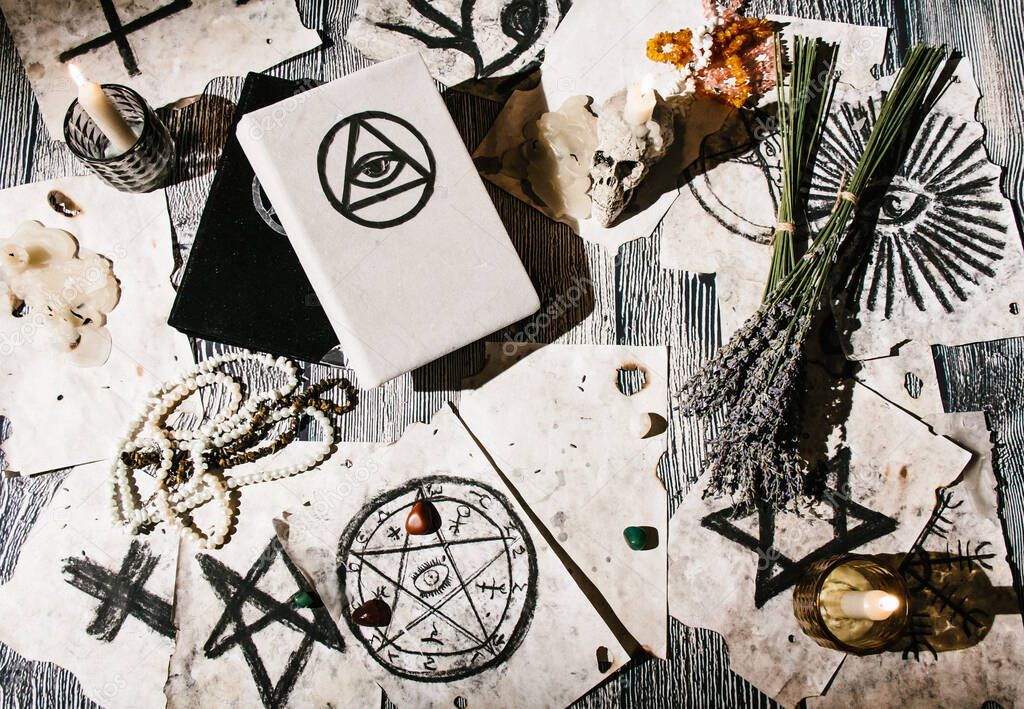 White magic book laying on the table with old manuscripts with occult symbols, candles, lavender. Concept of fortune telling