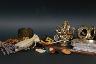 Siyah arka planda esrarengiz semboller. Aroma çubuğu, Ganesha biblosu, taş tespih. Üst görünüm