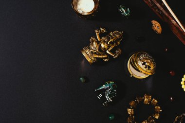 Siyah arka planda gizli semboller var. Aroma çubuğu, Ganesha biblosu, taş tespih. Üst görünüm, boş boşluk.