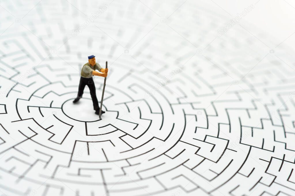 Miniature people: Worker man breaking down the walls in the maze. Concepts of  problem solving, challenge and Unexpected solutions concept. 