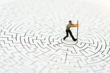 Minyatür insanlar: İşçi adam labirentteki duvarları yıkıyor. Problem çözme, meydan okuma ve beklenmeyen çözümler kavramı. 