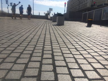 Artistik kaldırımda üç kişi yürüyor.