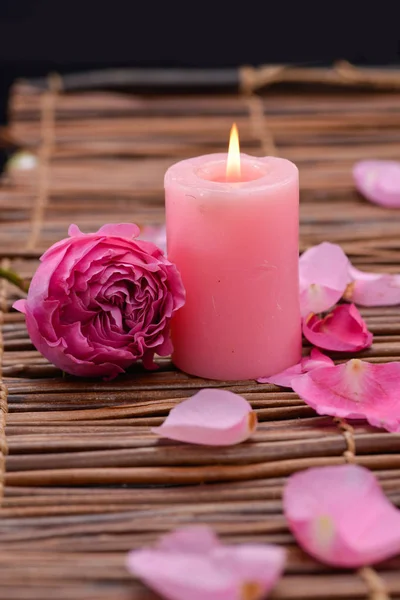 Pink rose with candle and petals on mat