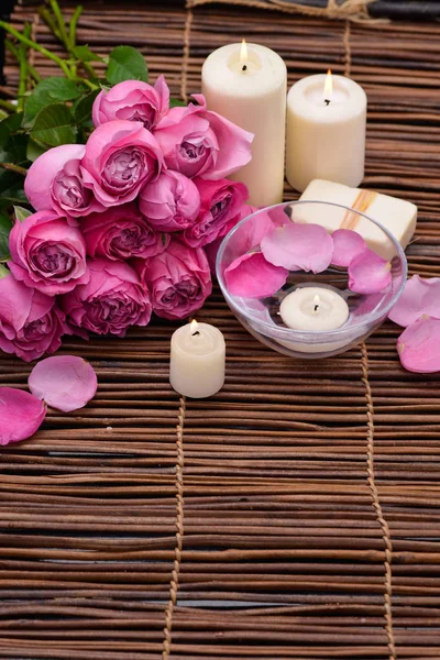Lying on Pink rose with candle and petals,bowl on mat