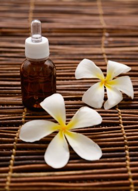Masaj yağı ve hasır arka plan ile iki frangipani