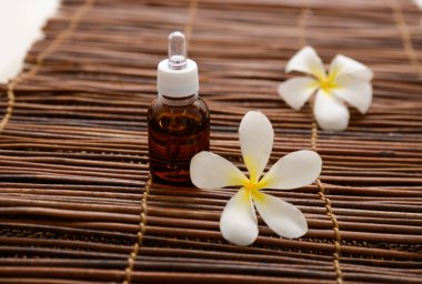 Masaj yağı ve hasır arka plan ile iki frangipani