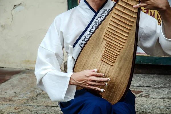 Bir adam Çin 'de Pipa adında bir müzik aleti çalıyor.