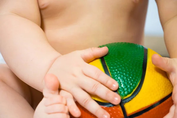 Közeli kép a babys kezében egy élénk színű labdát — Stock Fotó