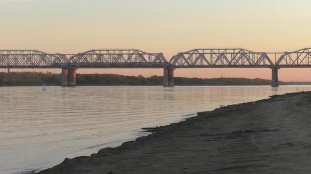 Yük treni akşam günbatımında Sibirya'da Nehri geçip köprüde. renk düzeltme olmadan video — Stok video