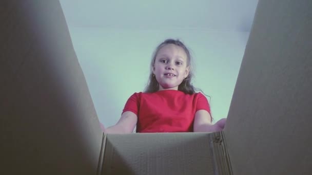 A little happy girl gets a gift from a cardboard box-a gentle Bengal kitten. cámara lenta — Vídeos de Stock