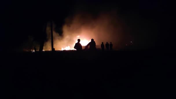 Яркое свечение огня ночью, силуэты людей, замедленная съемка — стоковое видео