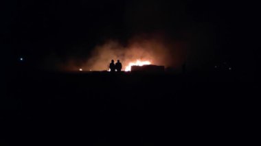 Gece parlayan bir ateş, insanların siluetleri, itfaiyecilerin işi, yavaş çekim