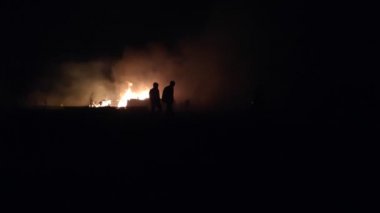 Gece parlayan bir ateş, insanların siluetleri, itfaiyecilerin işi, yavaş çekim