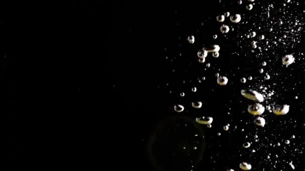 Λεμόνι πέφτει στο νερό σε μαύρο φόντο. αργή κίνηση — Αρχείο Βίντεο