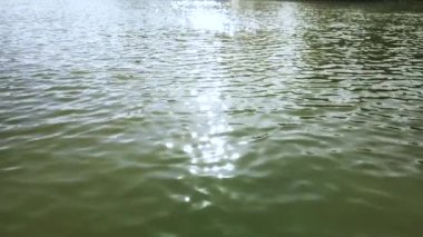 Göldeki suyun yüzeyinde güneş ışığı parlaması var. Şehir gölünün dalgalarında ışığın yansıması