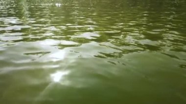 Göldeki suyun yüzeyinde güneş ışığı parlaması var. Şehir gölünün dalgalarında ışığın yansıması
