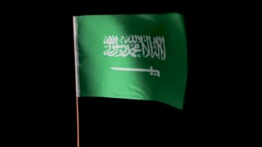 Suudi Arabistan 'ın ulusal bayrağı siyah bir arka planda rüzgarda dalgalanıyor.