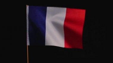 Fransa bayrağı siyah bir arka planda rüzgarda dalgalanıyor.