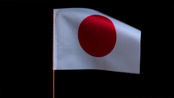 Державний прапор Японії летить вітром на чорному тлі. — стокове відео