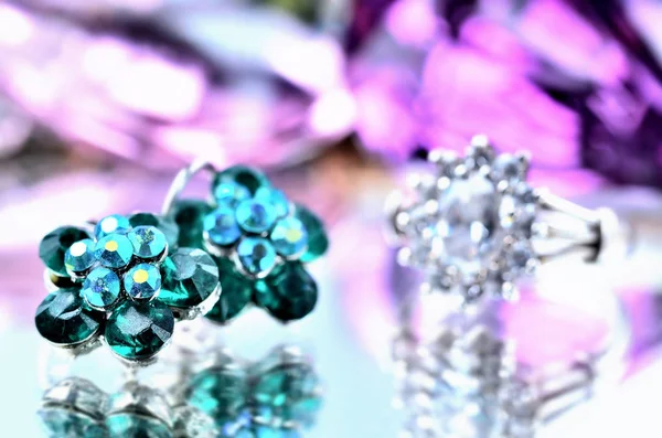 Nahaufnahme grüner blumenförmiger Ohrringe mit Gänse-Diamanten-Schmuck - Reflexionseffekt - Silberring im Hintergrund — Stockfoto