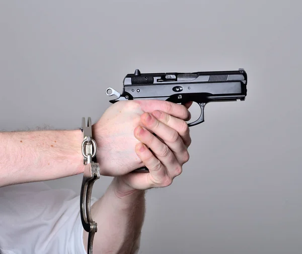 Händer med handfängsel pekar en pistol pistol isolerade — Stockfoto
